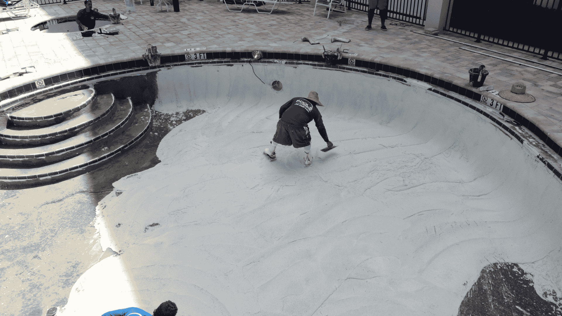 Crew resurfacing pool interior during renovation by Pools USA in Port St. Lucie, FL